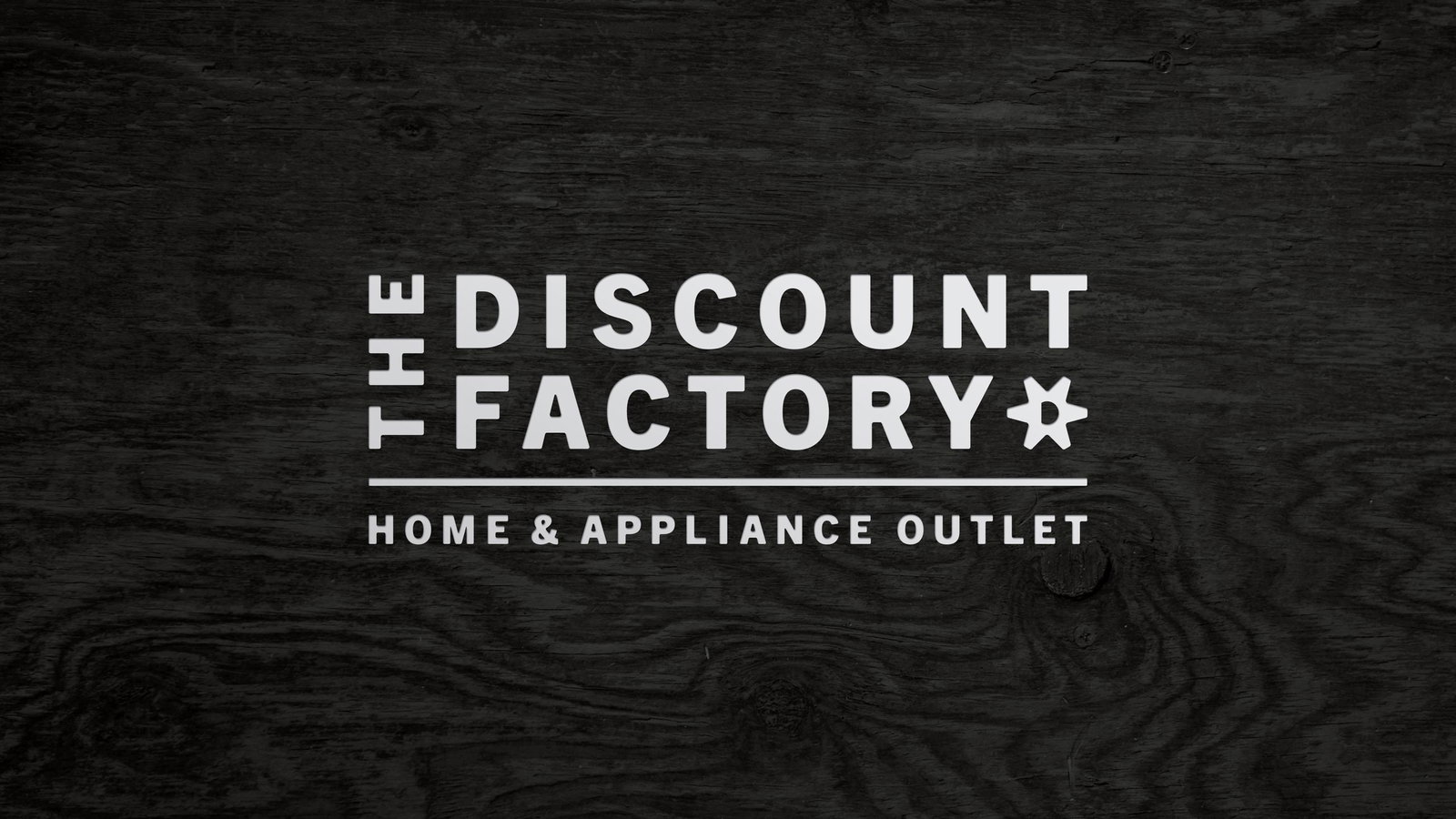 The Discount Factory Home & Appliance Outlet logo reversed out in white on a dark gray woodgrain texture
