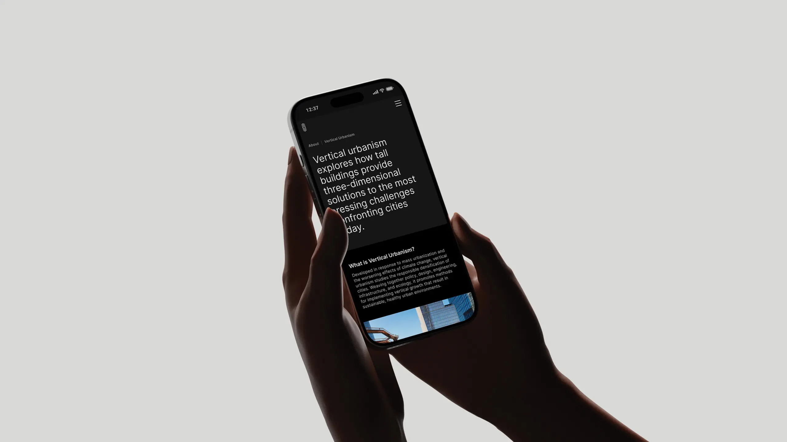 A person holds a smartphone with a black screen displaying text the about section on the Council for Vertical Urbanism website, highlighting tall buildings as solutions for city challenges.