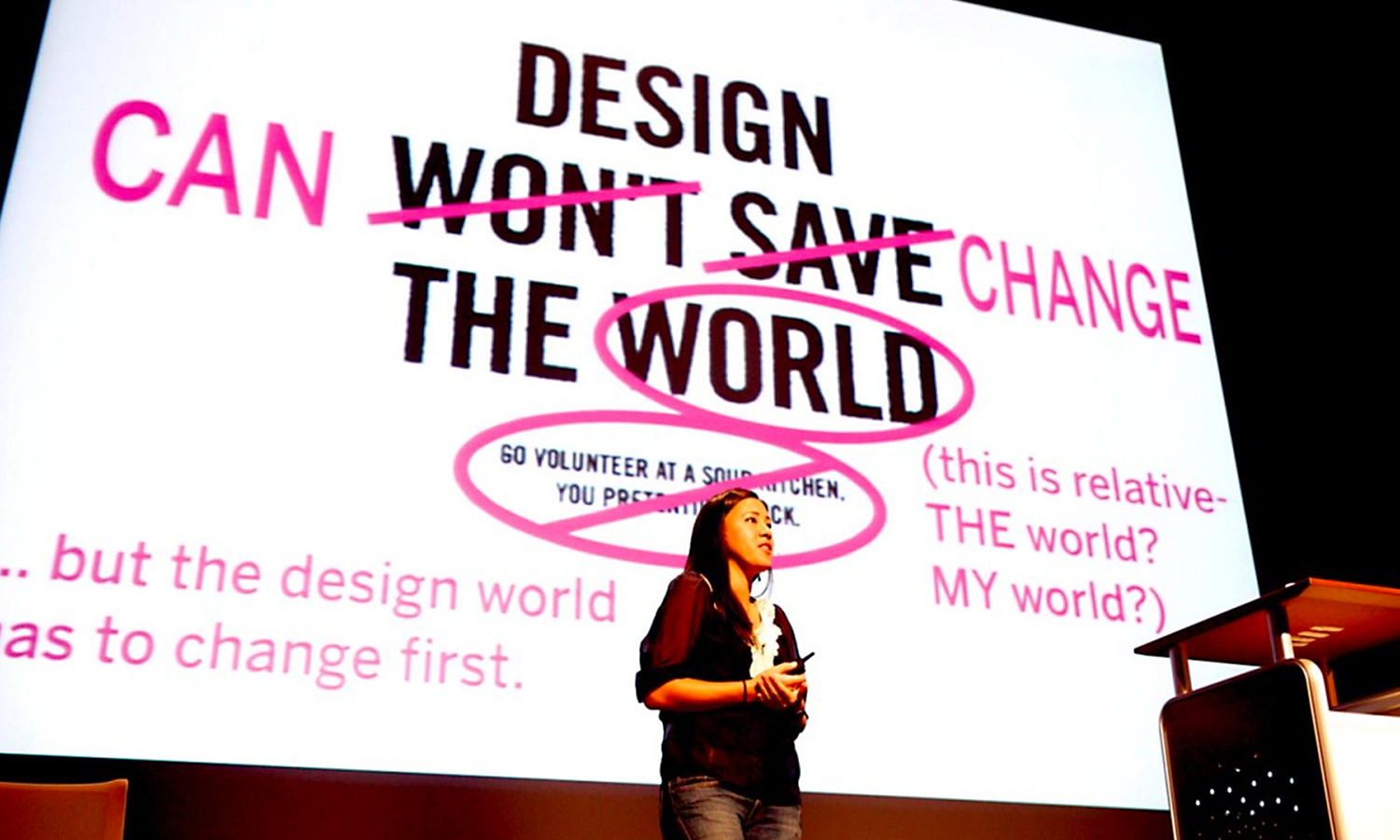 A speaker stands in front of a bold presentation slide at the Cusp conference reading, "Design CAN CHANGE the World" with crossed-out words. The tone is inspiring and thoughtful.