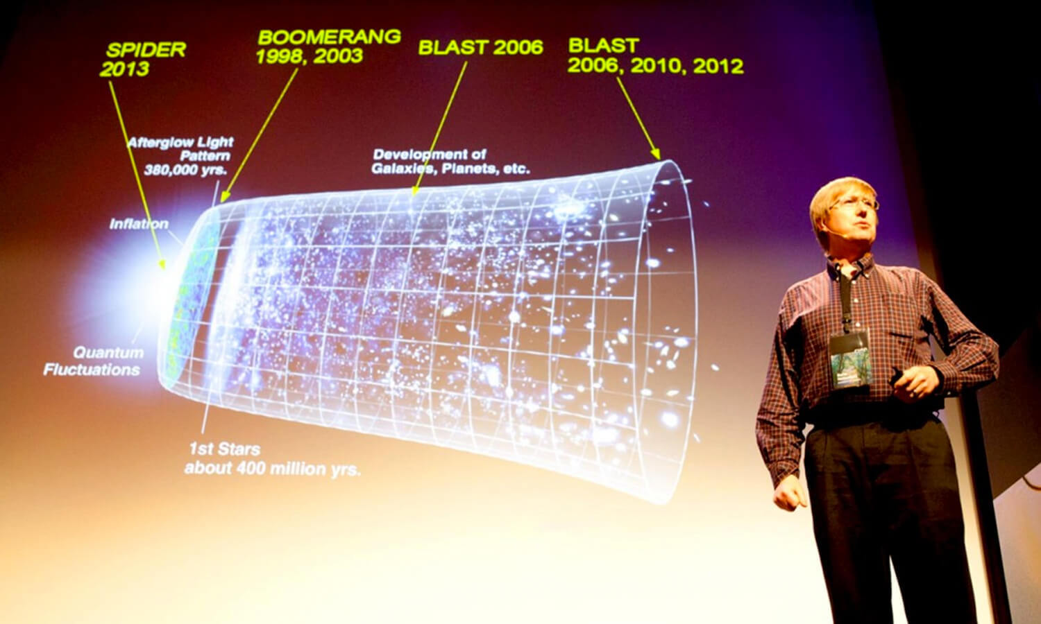 A man presents a cosmic timeline slide at the Cusp conference indicating the universe's expansion, featuring key milestones such as galaxy and planet formation.