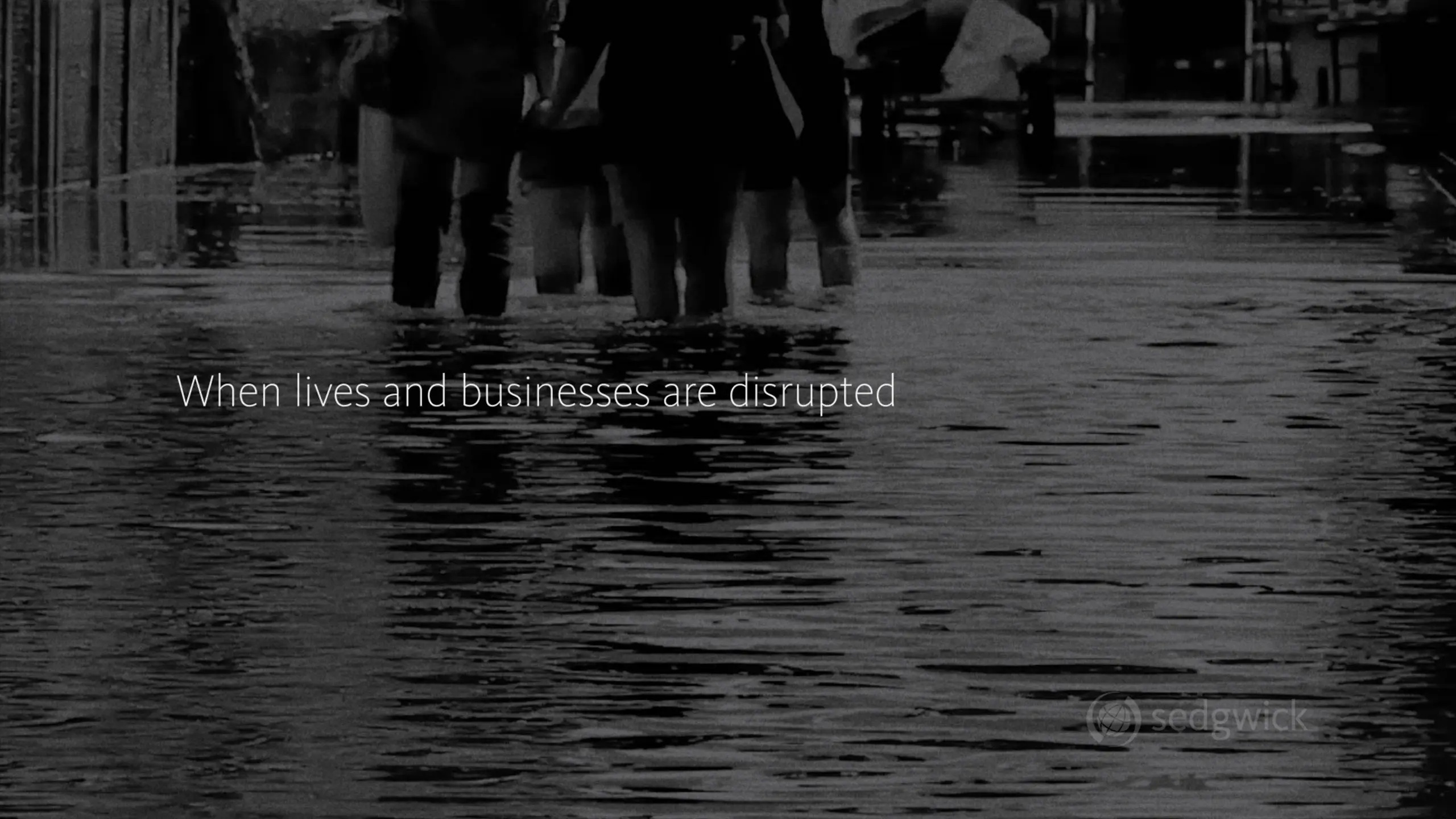 People wading through knee-deep floodwater on a city street. The text reads, "When lives and businesses are disrupted," conveying urgency and concern.