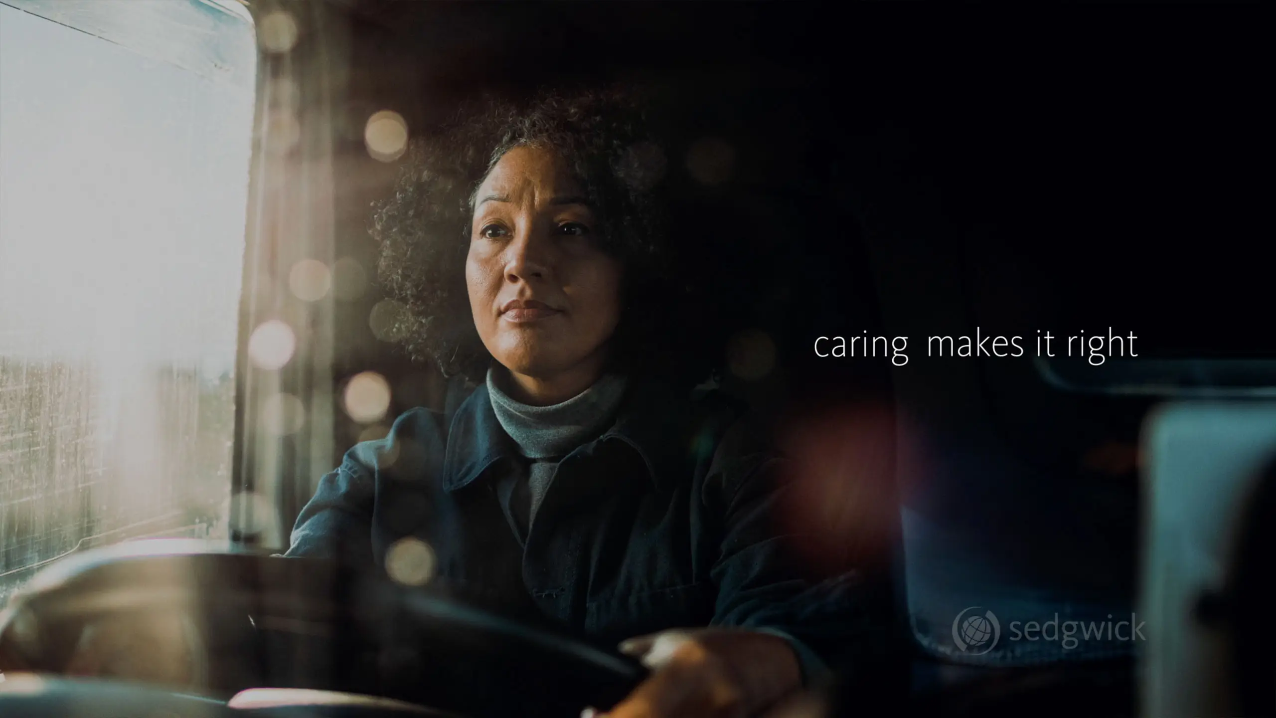 A woman with curly hair drives, gazing attentively through a sunlit window. Text reads "caring makes it right."