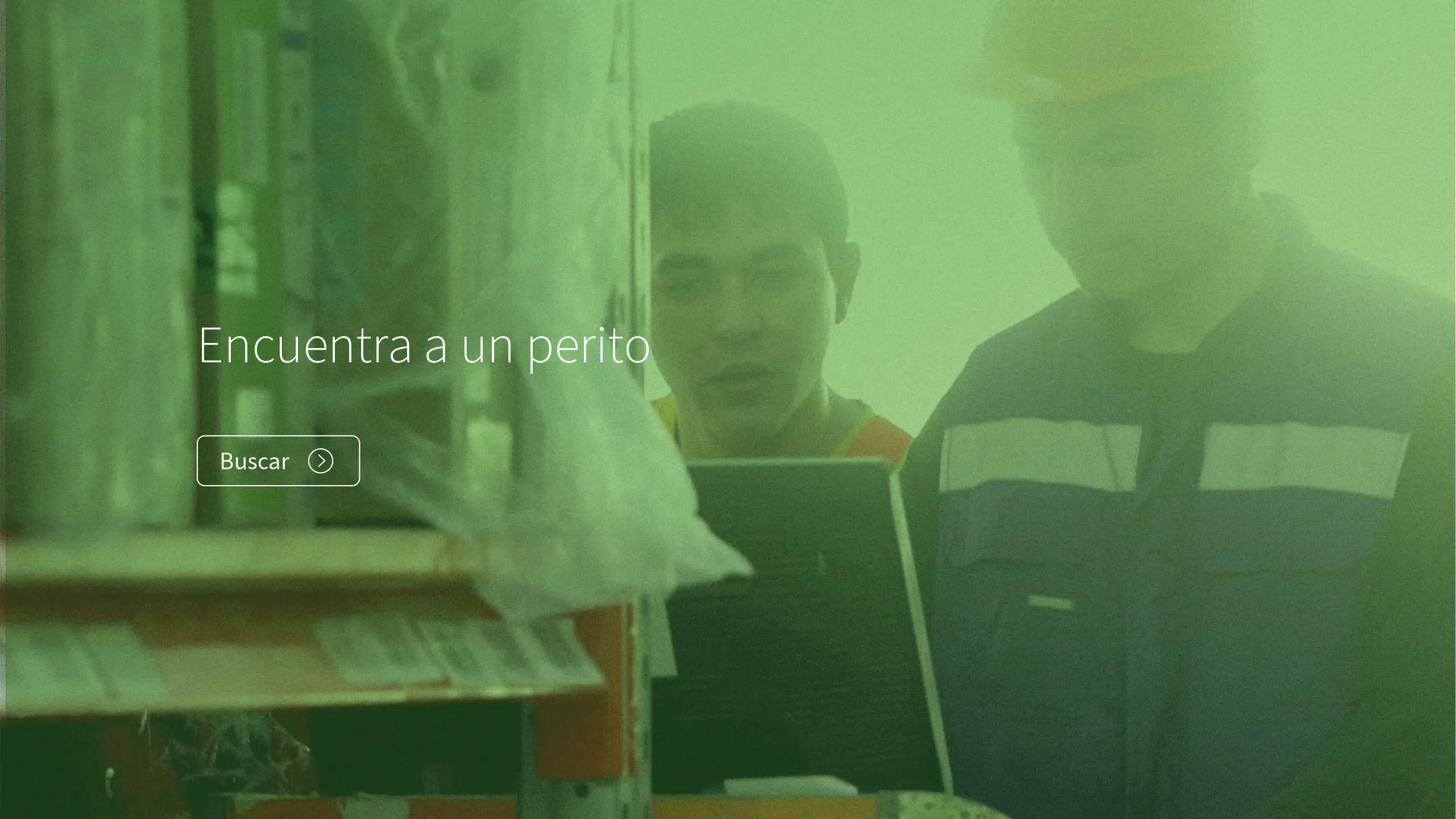 Snapshot of a webpage where two workers in safety gear look at a computer screen in a dim, green-lit industrial setting. Overlaid text reads, "Encuentra a un perito" with a search button.